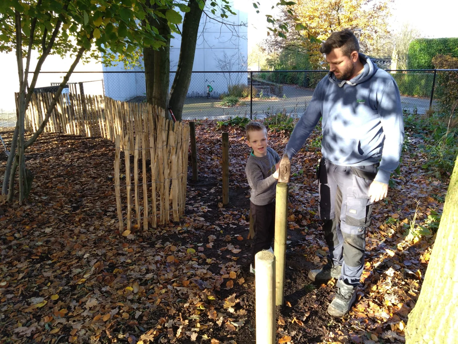 Een ouder en kind werken samen aan de natuurlijke omheining